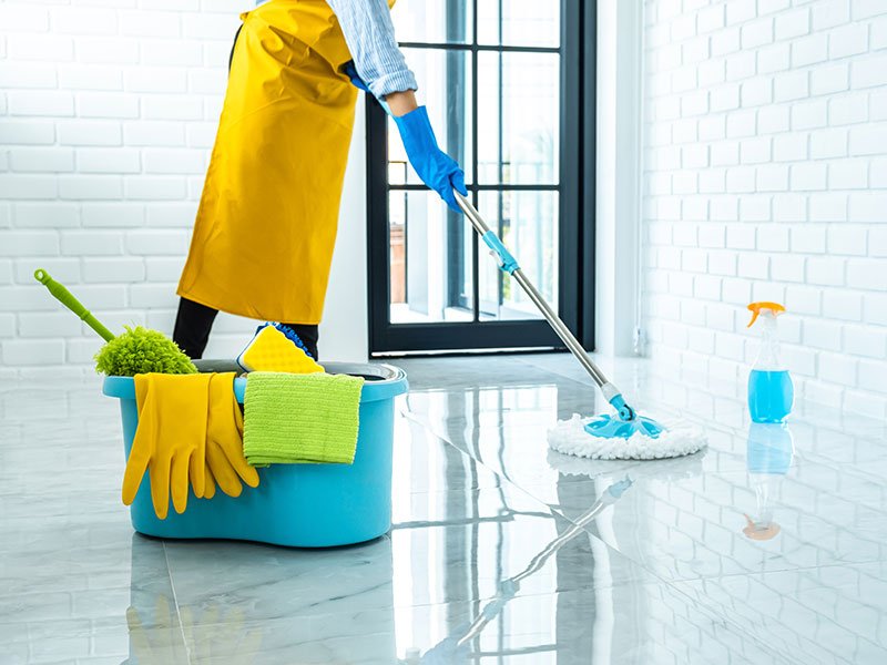 Various cleaning products and equipment arranged in modern space while cleaner mops floor.