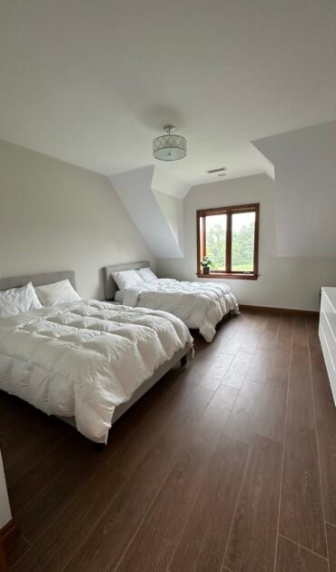Post-construction cleaning of a bright, spacious double-bed guest room with wood flooring