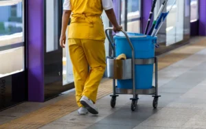 Custodian with cleaning cart in hallway