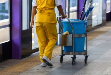 Custodian with cleaning cart in hallway