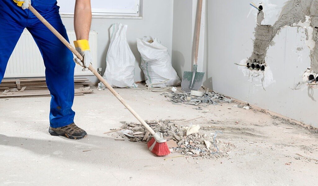 Worker sweeping debris at renovation site