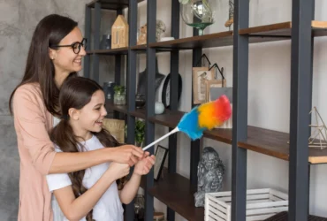 Mother and daughter dusting shelves together