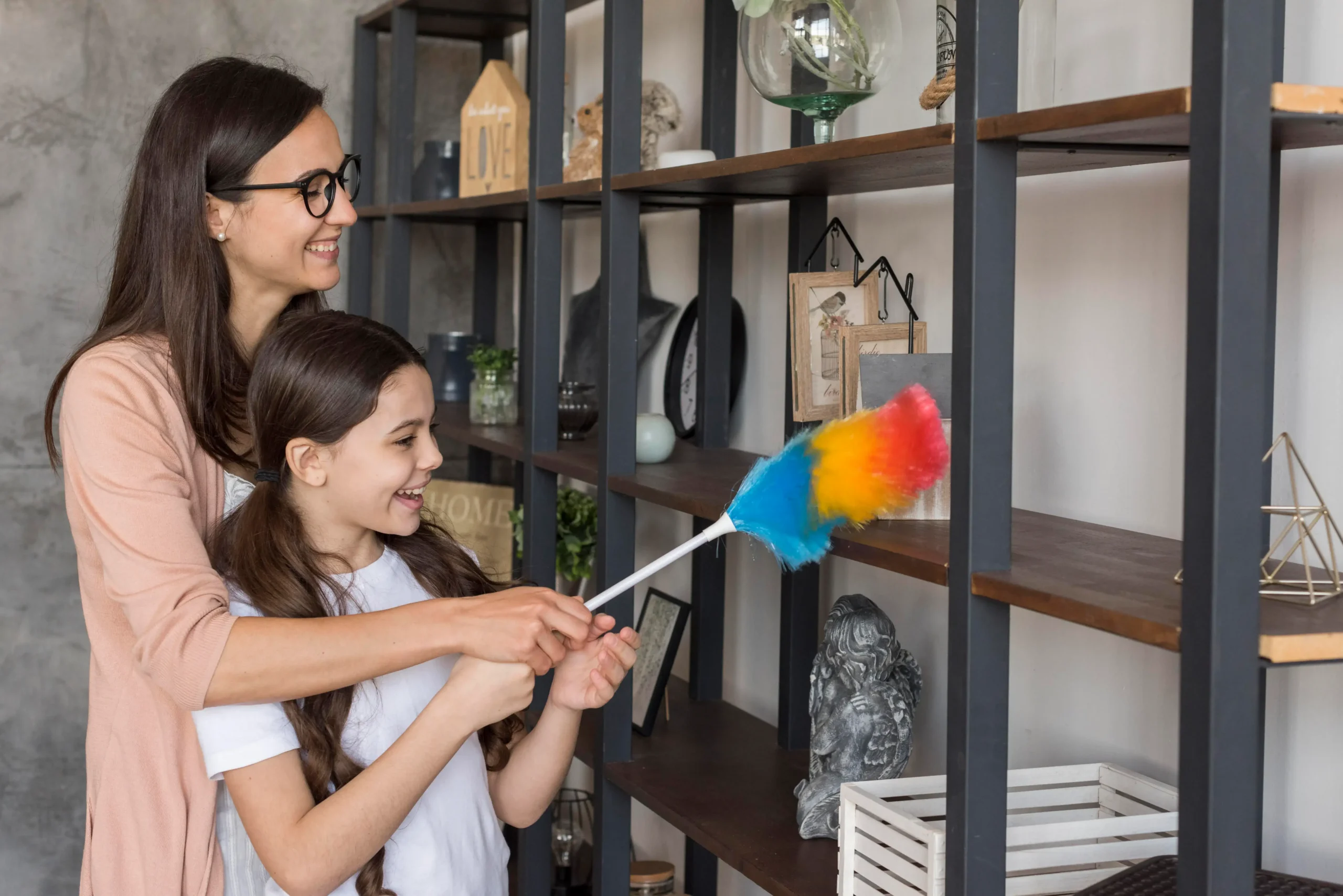 Mother and daughter dusting shelves together